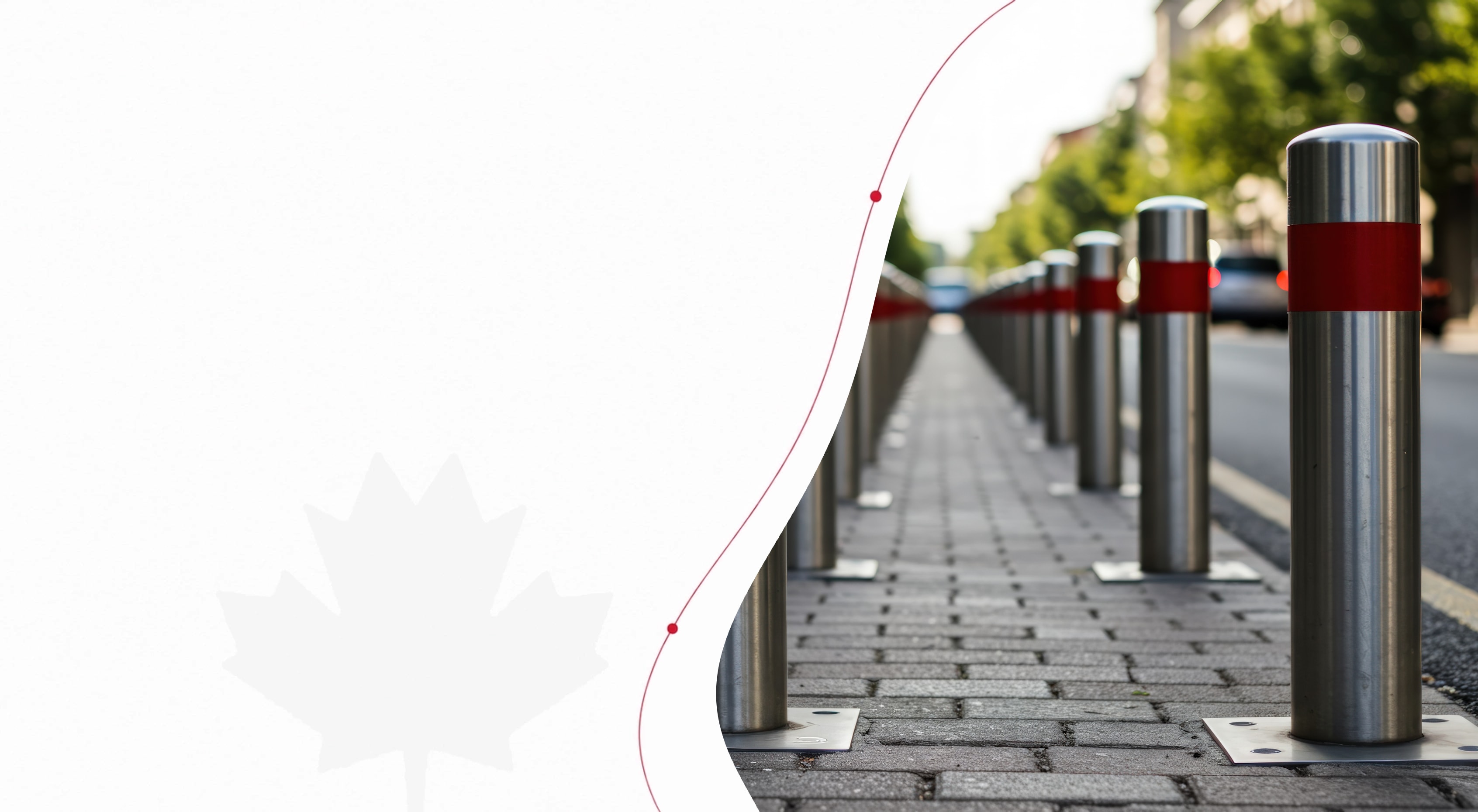 A row of stainless steel bollards with red bands lining a city sidewalk